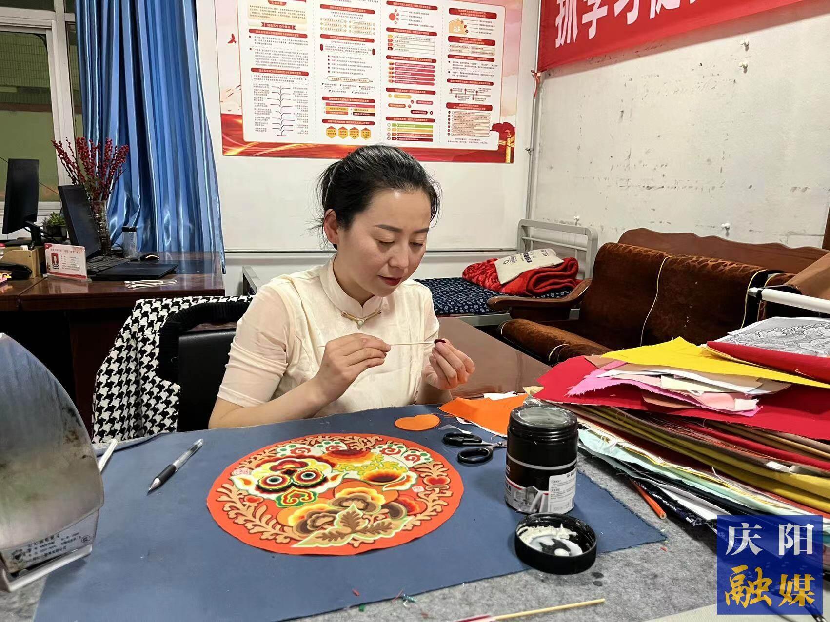 李慶英正在創(chuàng)作布貼畫作品。
